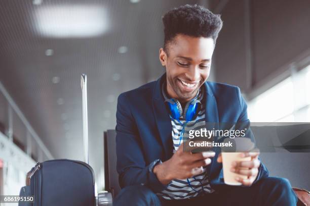 jonge man te wachten in de lounge van de luchthaven gebruik mobiele telefoon - airport hipster travel stockfoto's en -beelden