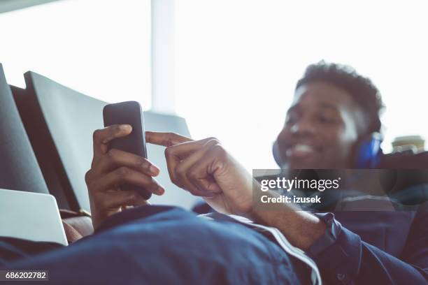 young man using mobile phone at airport lounge - business class reclining plane stock pictures, royalty-free photos & images