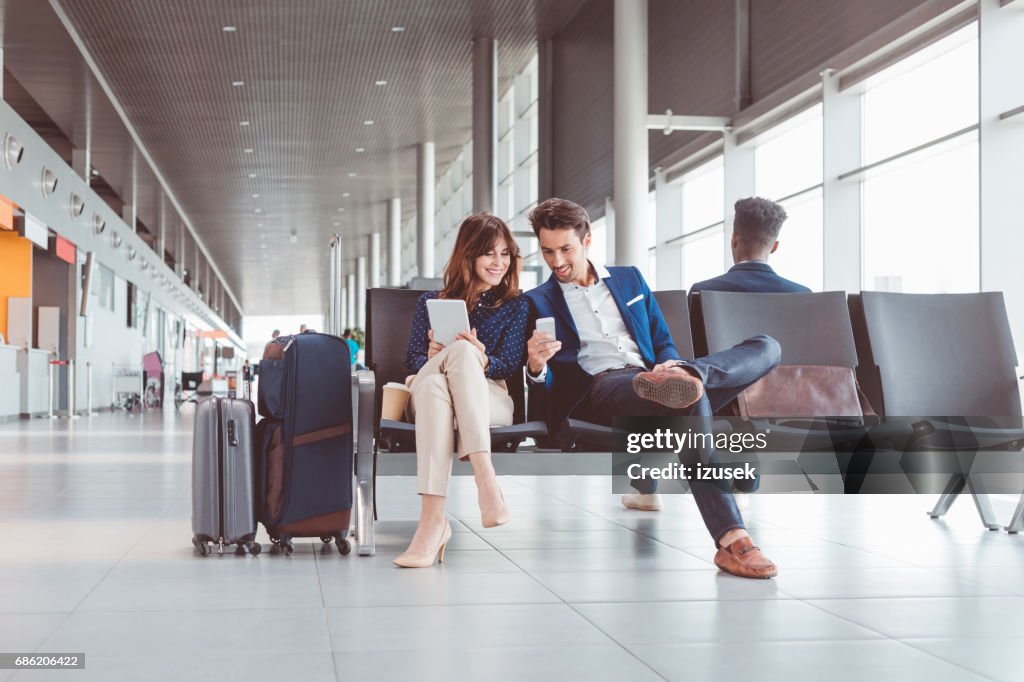 Business couple waiting for flight at airport lounge