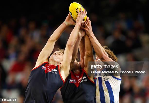 Oscar McDonald and Cameron Pedersen of the Demons compete for the ball against Ben Brown of the Kangaroos during the 2017 AFL round 09 match between...