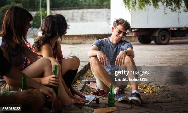 group of young friends sitting in park, drinking beer - adrenaline park stock pictures, royalty-free photos & images