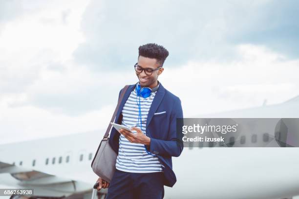young  businessman using a digital tablet in front of airplane - plane passenger stock pictures, royalty-free photos & images