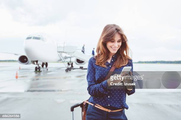 business-frau mit einem smartphone vor flugzeug - business jet stock-fotos und bilder