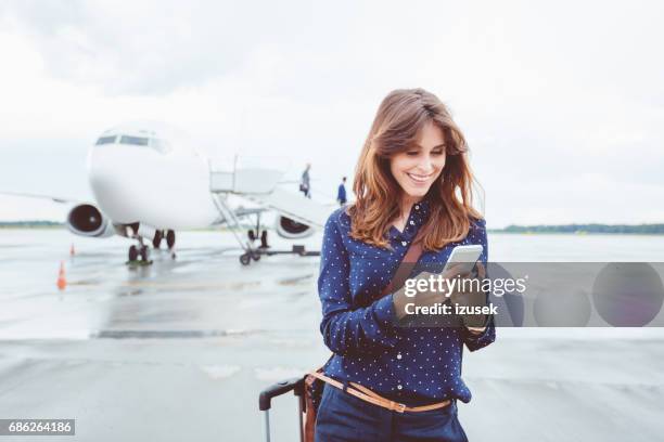 zakenvrouw met behulp van een slimme telefoon vóór vliegtuig - airport outside stockfoto's en -beelden