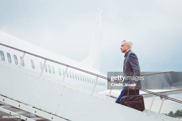 rijpe zakenman aan boord vliegtuig - boarding plane stockfoto's en -beelden