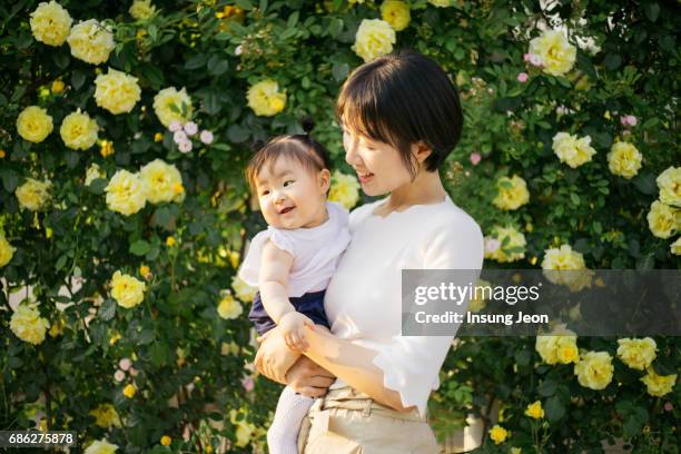 happy mother playing with daughter in park - korean baby girl stock-fotos und bilder