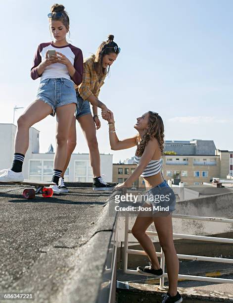 teenage girls climbing on rooftop parking lot - 3 teenagers mobile outdoors stock-fotos und bilder