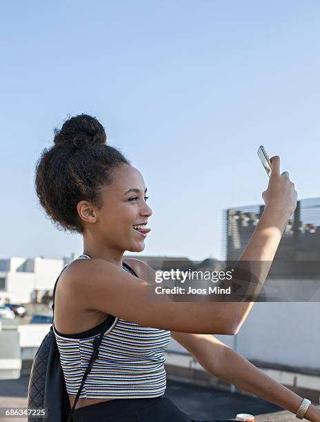teenage girl taking a selfie on rooftop - girl mobile stock-fotos und bilder