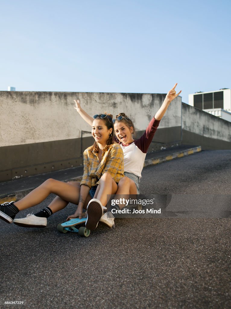 Teenage girls using skateboard on rooftop car park