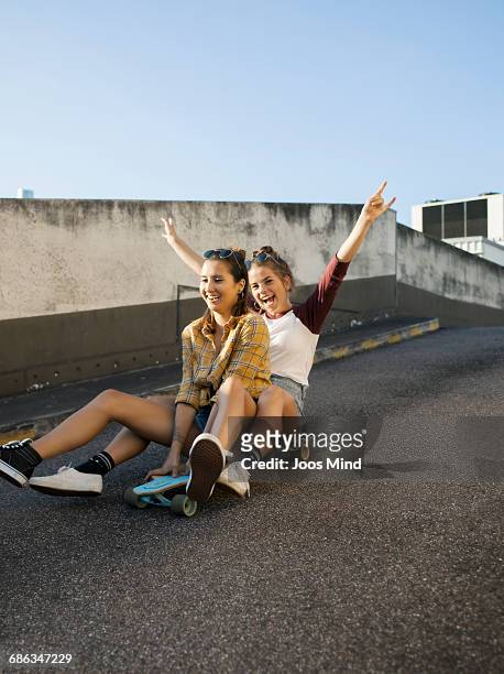 teenage girls using skateboard on rooftop car park - hip friends stock pictures, royalty-free photos & images