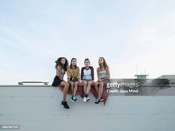 teenage girls sitting on rooftop wall - sitzen stock-fotos und bilder