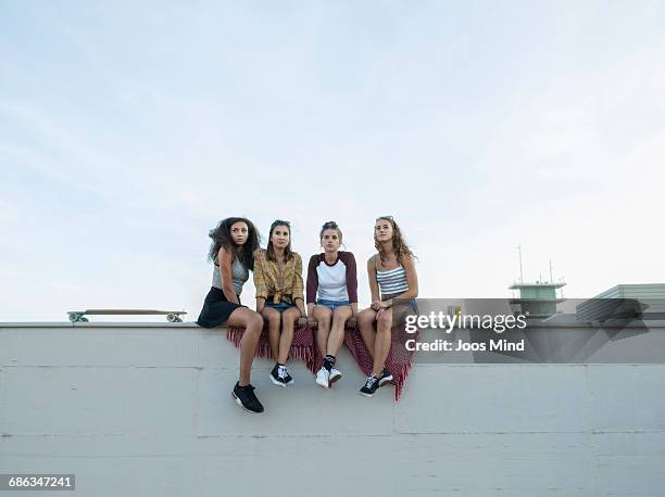 teenage girls sitting on rooftop wall - women in daisy dukes ストックフォトと画像