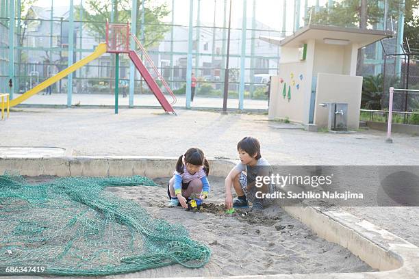 children playing at a sandpit - sandkasten stock-fotos und bilder