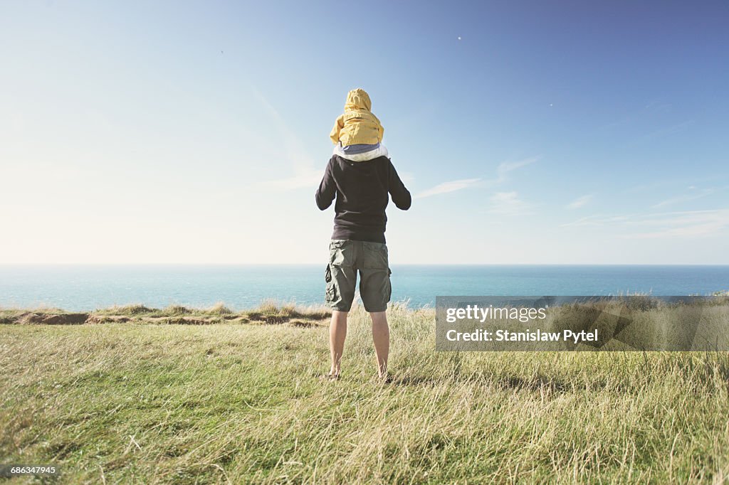 Father piggybacking kid near ocean