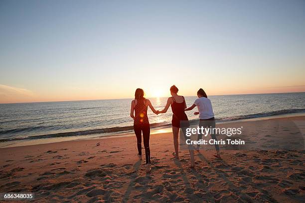 teenage girls walking on beach at sunset - sylt stock-fotos und bilder