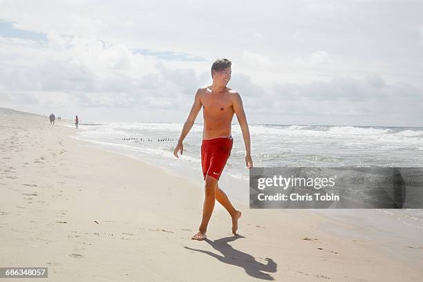 teenage boy on the beach - zwembroek stockfoto's en -beelden