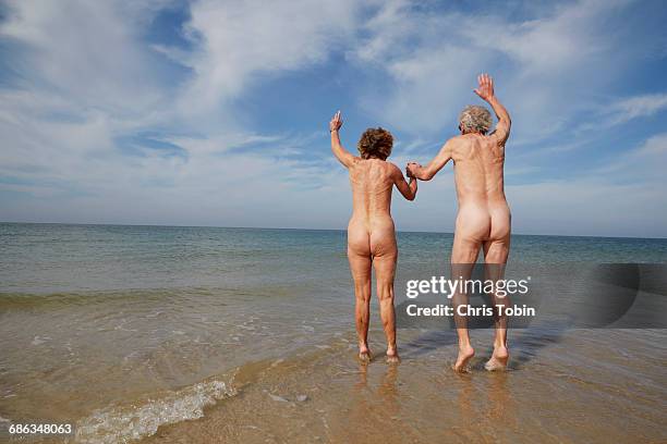 nude older couple jumping in water - birthday suit stock-fotos und bilder