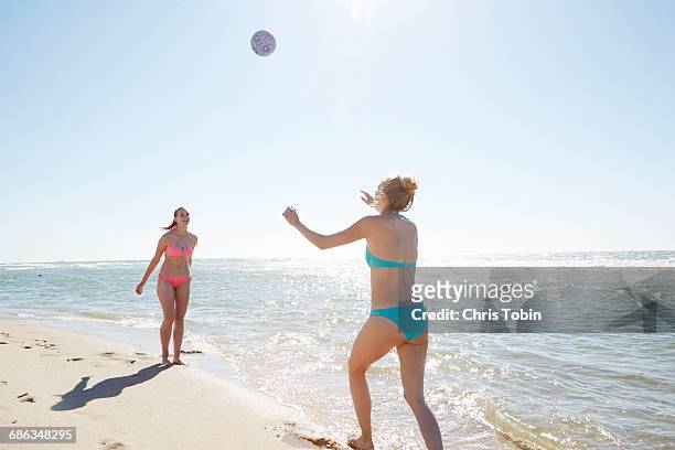 girls playing volleyball at water's edge - girls beach volleyball stock pictures, royalty-free photos & images
