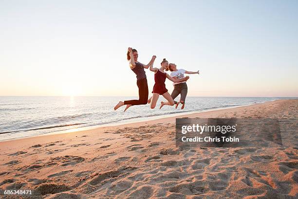 teenage girls jumping at beach - three girls at beach stock pictures, royalty-free photos & images