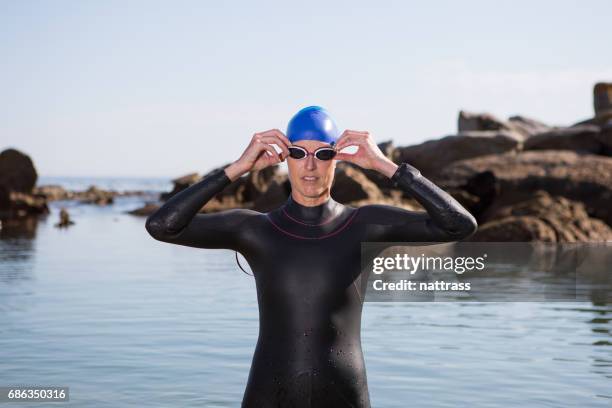 fit adult woman in her wetsuit and swimming gear - triathlon gear stock pictures, royalty-free photos & images