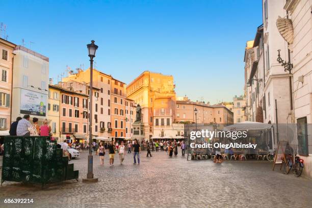 campo de' fiori voller touristen und statue von giordano bruno bei sonnenuntergang, rom, italien. - blumenfeld stock-fotos und bilder