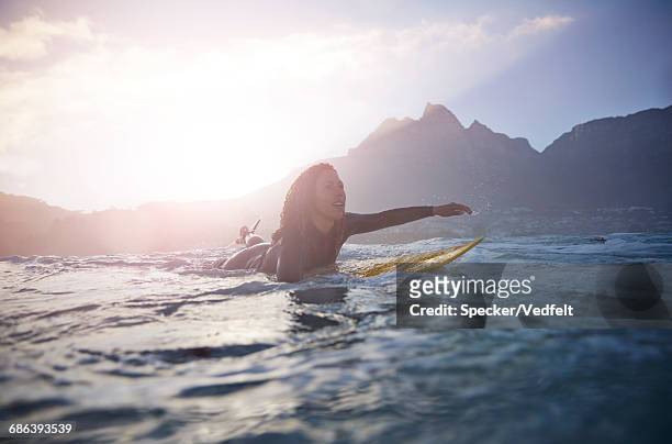 female surfer paddling at sunrise - prancha de surf imagens e fotografias de stock