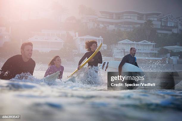 group of surfers running out in the ocean - woman surfboard stockfoto's en -beelden