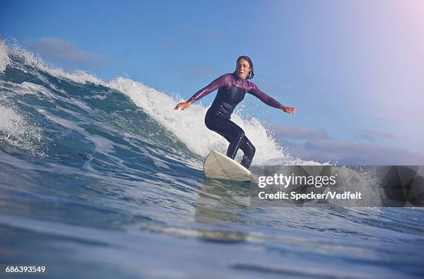 surfer riding wave at sunrise - surf fotografías e imágenes de stock