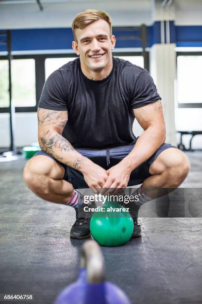 hockend von kettlebell im fitness-studio fitness-trainer - junger mann allein stock-fotos und bilder