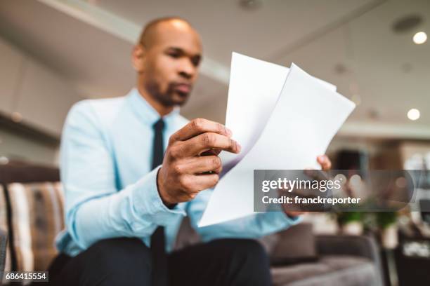 businessman reading rading the bills at home - reviewing document stock pictures, royalty-free photos & images