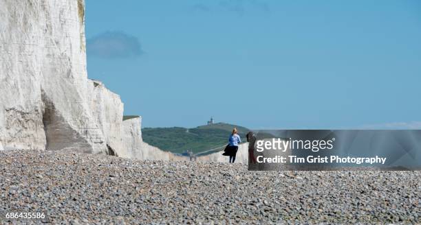 hikers at the seven sisters cliffs - lighthouse rolling landscape foto e immagini stock