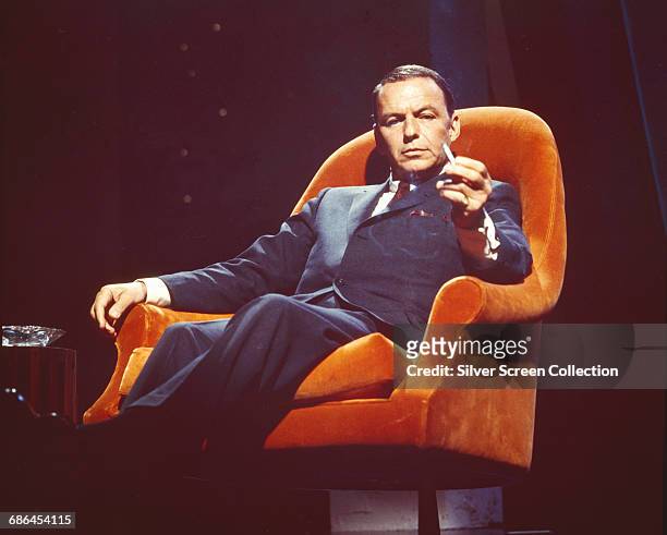 American actor and singer Frank Sinatra in an orange armchair, circa 1955.