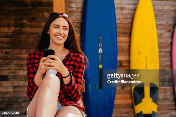 beautiful woman texting at a beach bar - dar uma ajuda imagens e fotografias de stock