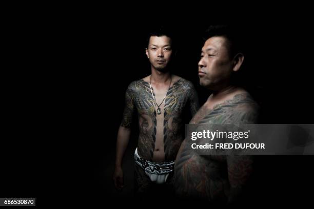 In this picture taken on May 20 men pose for photographs showing their "Irezumi" Japanese traditional tattoos related to the Yakuza's universe,...