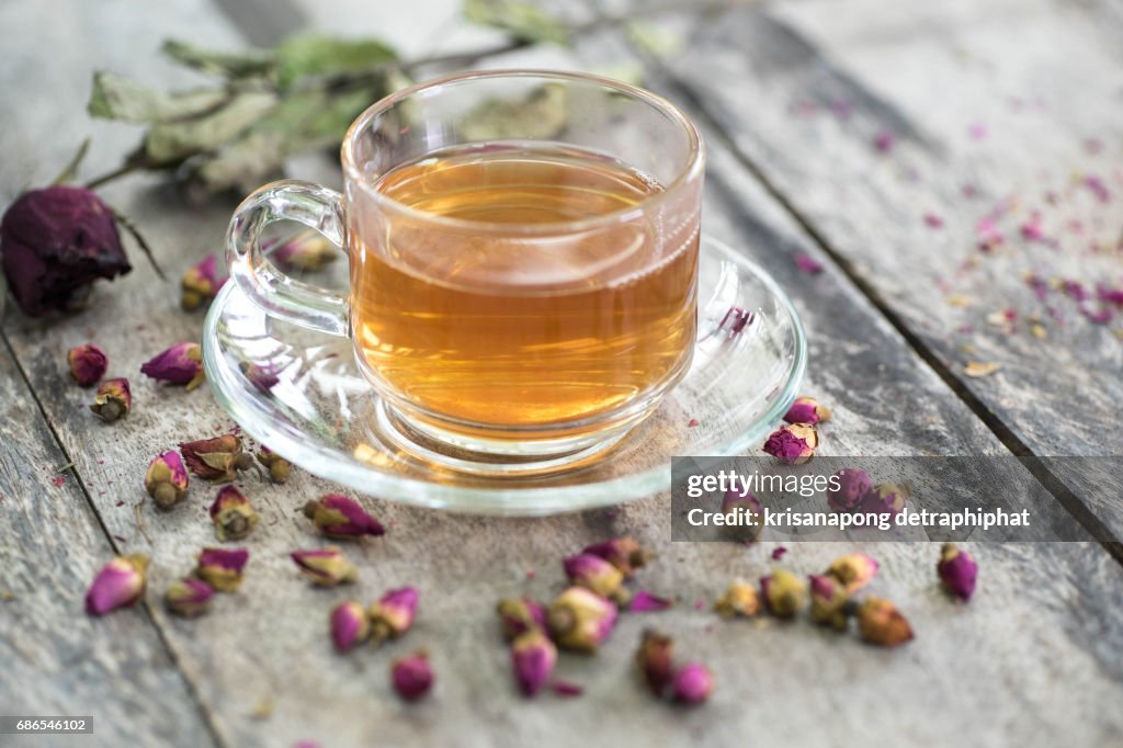 Tea made from tea rose petals in a glass bowl on wooden  background