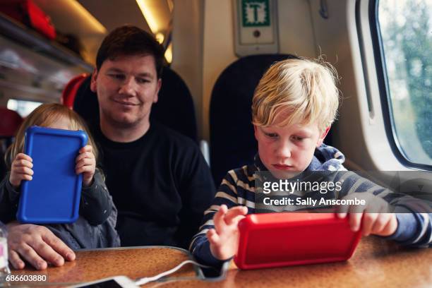 family using digital tablets on the train - train interior stock pictures, royalty-free photos & images