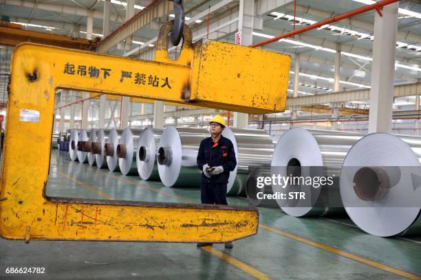 This photo taken on May 20, 2017 shows a Chinese worker loading aluminium tapes at an aluminium production plant in Huaibei, east China's Anhui...