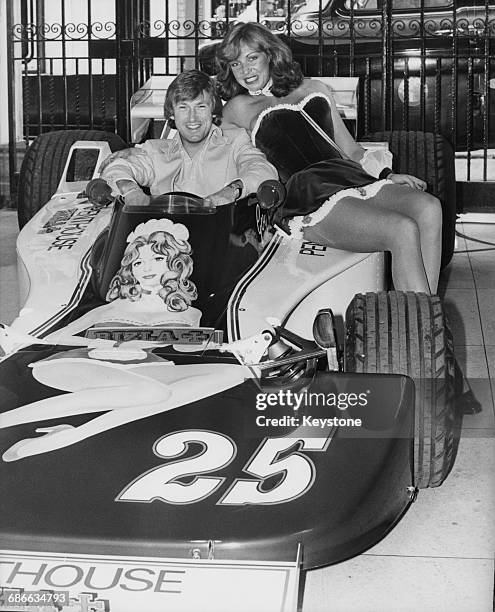 Racing driver Guy Edwards of Great Britain sits aboard the Penthouse Rizla Racing Hesketh 308D Ford Cosworth DFV V8 whilst model Suzanne Turner whose...