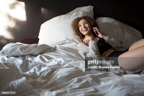 young woman on phone in bed - victorias secret photos - fotografias e filmes do acervo