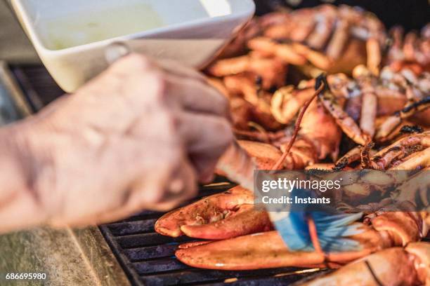 woman, using a brush, is basting canadian lobsters with olive oil to grill them on the barbecue. - basted stock pictures, royalty-free photos & images