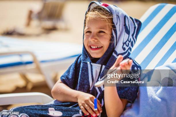 smiling little girl in bathrobe relaxing on the beach - robe stock pictures, royalty-free photos & images