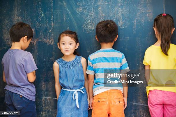 a group of children in school. four children standing by the blackboard. - 子供のみ ストックフォトと画像