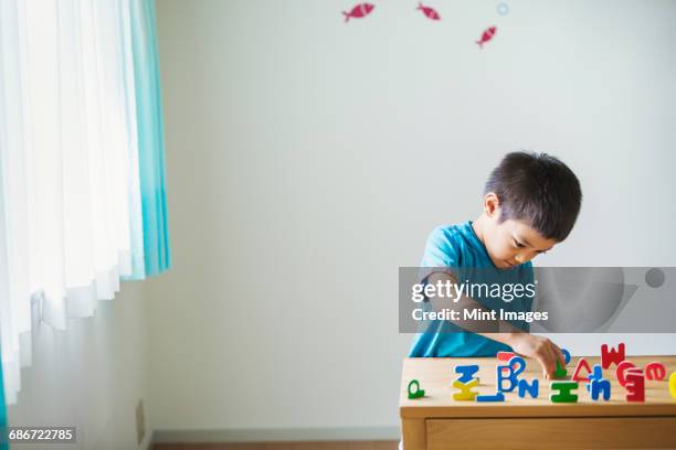 a boy playing with colourful alphabet letters. - solo bambini foto e immagini stock