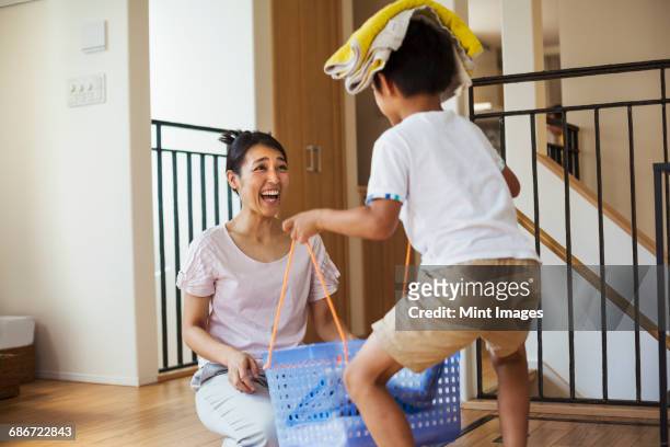 family home. a woman and her son sorting the laundry, the boy balancing towels on his head.  - children housework stock pictures, royalty-free photos & images