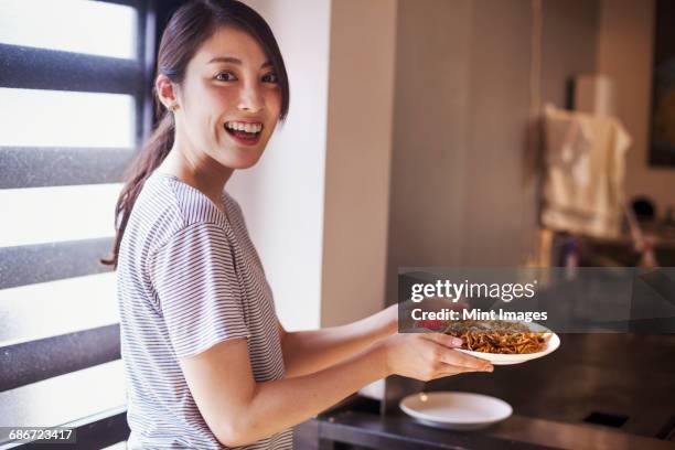 woman holding a plate of soba noodles in a noodle shop. - japan food stock pictures, royalty-free photos & images