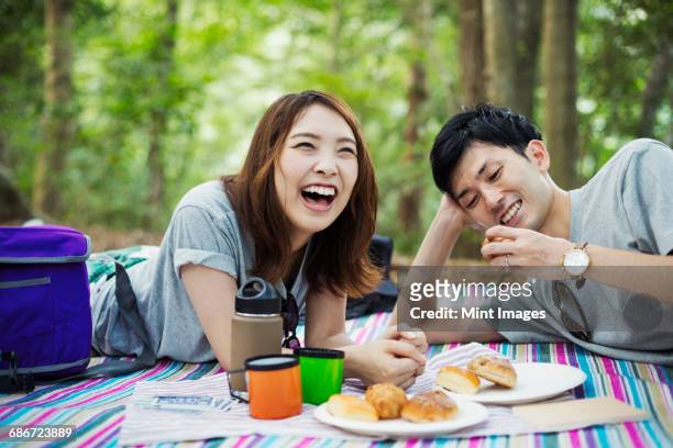 young woman and man having a picnic in a forest. - レジャーシート ストックフォトと画像