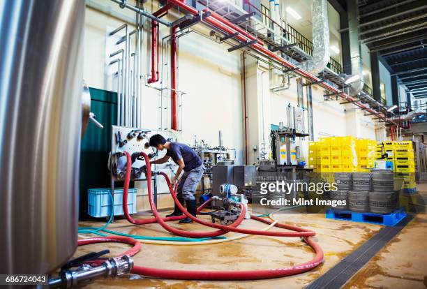 man working in a brewery, connecting hoses to a metal beer tank. - 郷土料理　日本 ストックフォトと画像