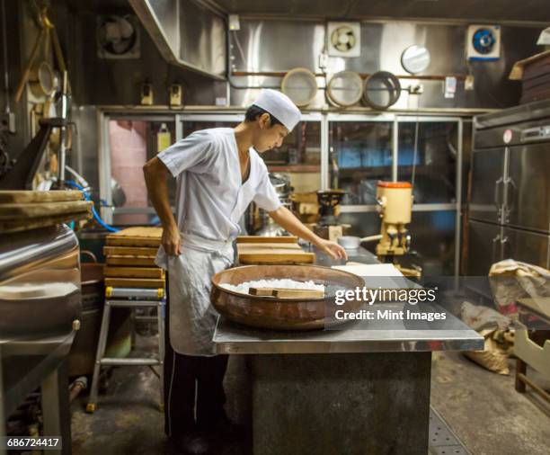 a small artisan producer of wagashi. a man mixing a large bowl of ingredients and pressing the mixed dough into moulds in a commercial kitchen. - japanese sweet stock-fotos und bilder