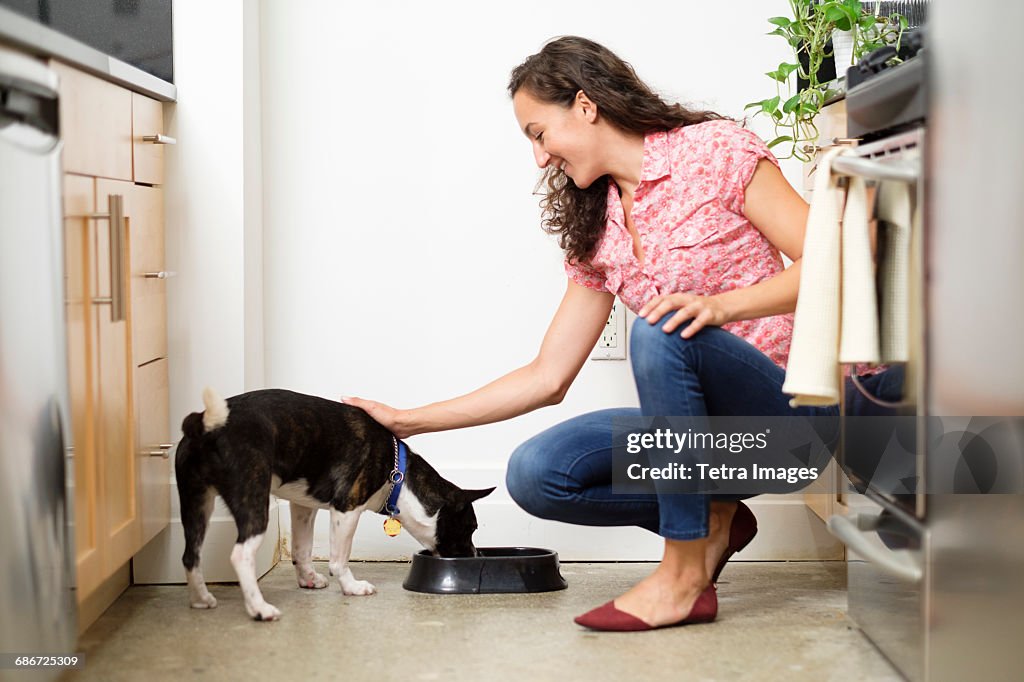 Woman feeding dog in kitchen