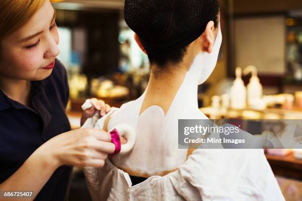 a modern geisha or maiko woman being prepared in traditional fashion, with white face makeup. - geisha in training stock pictures, royalty-free photos & images